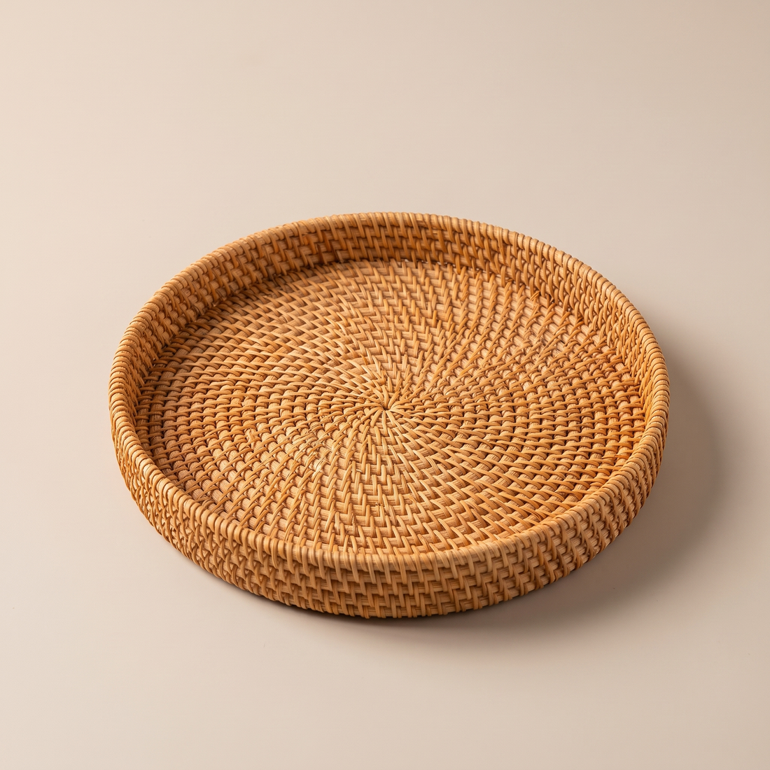 Round hand-woven rattan tray styled beneath a grouping of decorative storage boxes