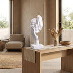 White abstract face sculpture on a neutral bookshelf beside ceramics