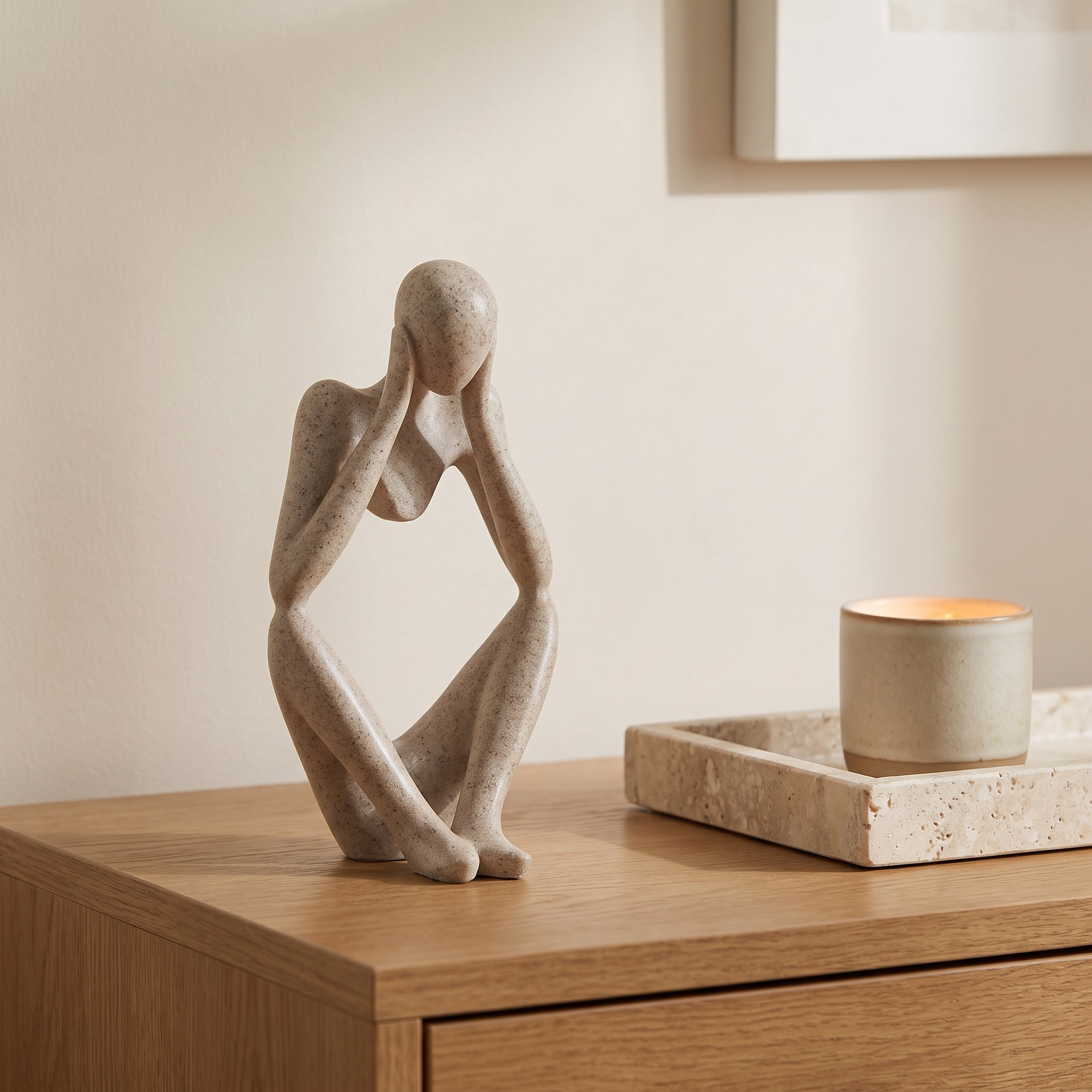 Sand-toned Thinker resin sculpture beside ceramics and books