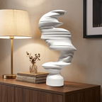 White abstract mask-profile resin sculpture on a living room console beside a lamp