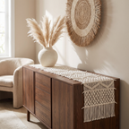 Cream bohemian macramé runner on a dark-wood buffet with a pampas vase