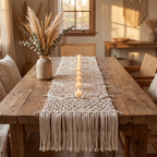 Cream bohemian macramé table runner with a row of tea-lights and pampas on a reclaimed-wood table