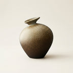 Sandstone matte speckled stoneware bottle vase with flared saucer-rim neck, on a warm-white studio backdrop