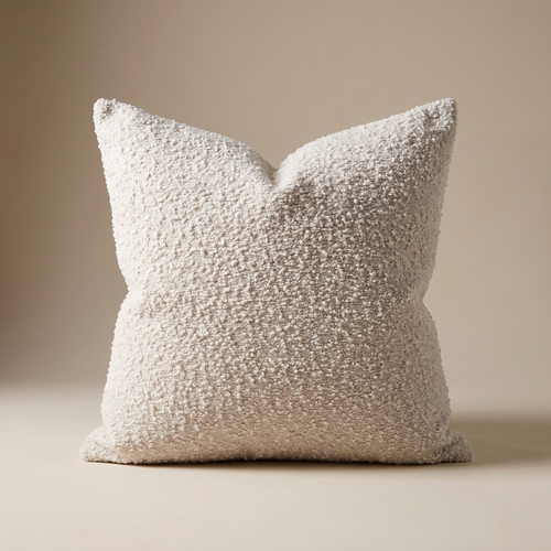 Ivory bouclé cushion cover resting on a linen sofa in soft daylight