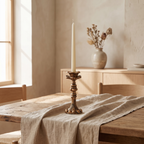 Vintage bronze candlestick with a lit ivory taper on a wooden mantel