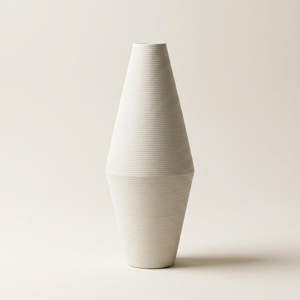 Matte white fine-ribbed ceramic Nordic vase, tall diamond spindle shape, on a warm-white studio background