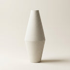 Matte white fine-ribbed ceramic Nordic vase, tall diamond spindle shape, on a warm-white studio background