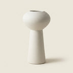Matte white fine-ribbed ceramic Nordic vase, footed pedestal hourglass shape, on a warm-white studio background