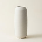 Matte white fine-ribbed ceramic Nordic vase, tall tapered shape, on a warm-white studio background