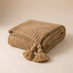 Chunky knit throw blanket in khaki draped over a linen sofa