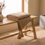 White chunky knit blanket layered across a made bed