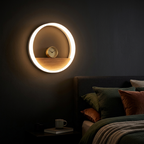 White ring shelf wall lamp beside a bed with a clock on its shelf at night