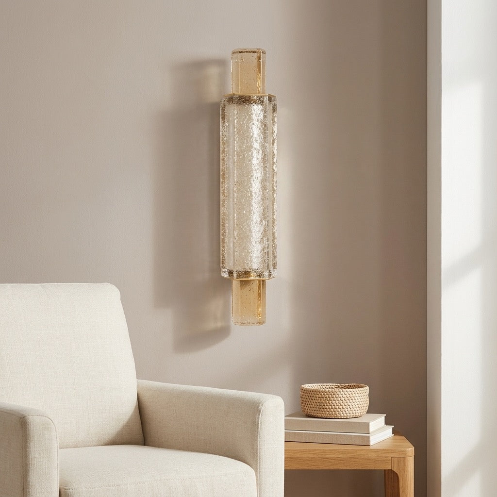 Postmodern champagne crystal-effect glass column sconce glowing warm against a wall