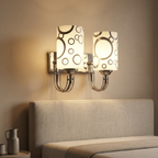 Chrome double-head wall sconce with two patterned glass shades above a bed