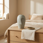 Grey-green mask vase as a sculptural object on a bedroom dresser