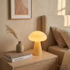 Beige glass mushroom lamp glowing on a bedside nightstand