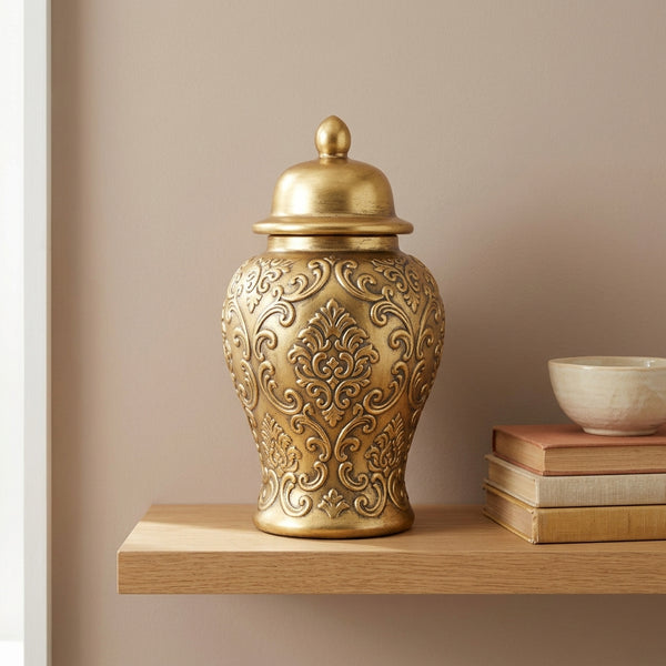gold-tone vintage ginger jar vase with embossed damask relief and domed lid on a wood shelf