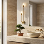 Nordic luxe black-and-gold wall sconce — above travertine bathroom vanity