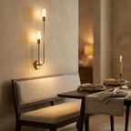 Nordic luxe black-and-gold wall sconce — above dining bench in warm ambience
