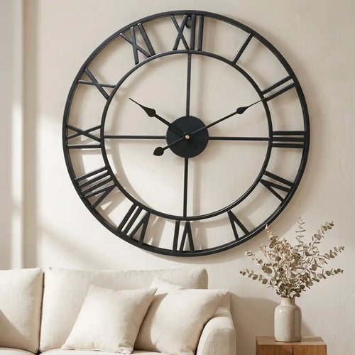 3D Roman numeral metal wall clock — on plaster gallery wall above linen sofa
