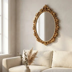 Gold oval vintage hanging wall mirror — on plaster gallery wall above linen sofa