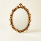 Gold oval vintage hanging wall mirror — on warm cream studio backdrop