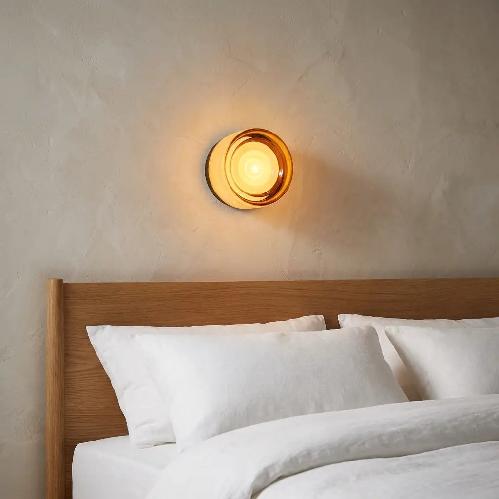 Round opal glass wall sconce — above oak headboard with linen bedding