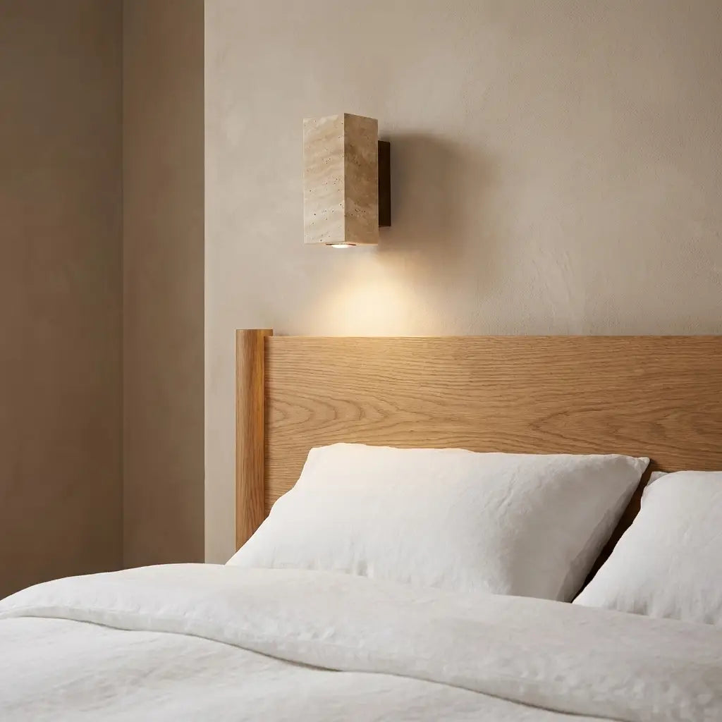 Wabi-Sabi travertine wall lamp — above oak headboard with linen bedding