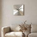 Stainless steel wall clock — on plaster gallery wall above linen sofa