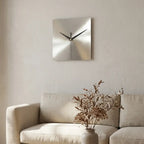 Stainless steel wall clock — on plaster gallery wall above linen sofa