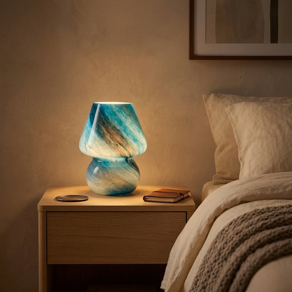 Blue Earth-design marbled glass mushroom lamp glowing on a wood bedside nightstand
