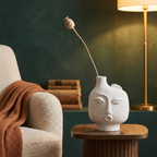 White ceramic face vase with a single stem on a side table in a reading nook
