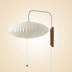 Flying-saucer wall lamp mounted beside a bed for soft ambient light