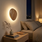 Oval natural wood wall light with warm backlit halo above a bedroom nightstand