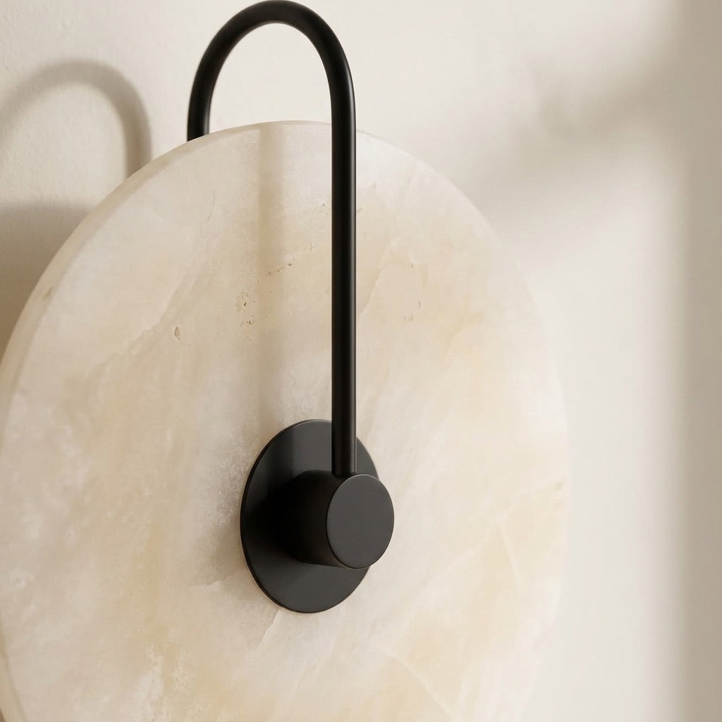 Close-up of the alabaster-look glowing disc and dark center hub of the wall sconce