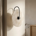 Alabaster-look moon disc wall sconce casting warm ambient light on the wall