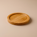 Round natural bamboo mini tray holding a ceramic coffee cup on a wood table