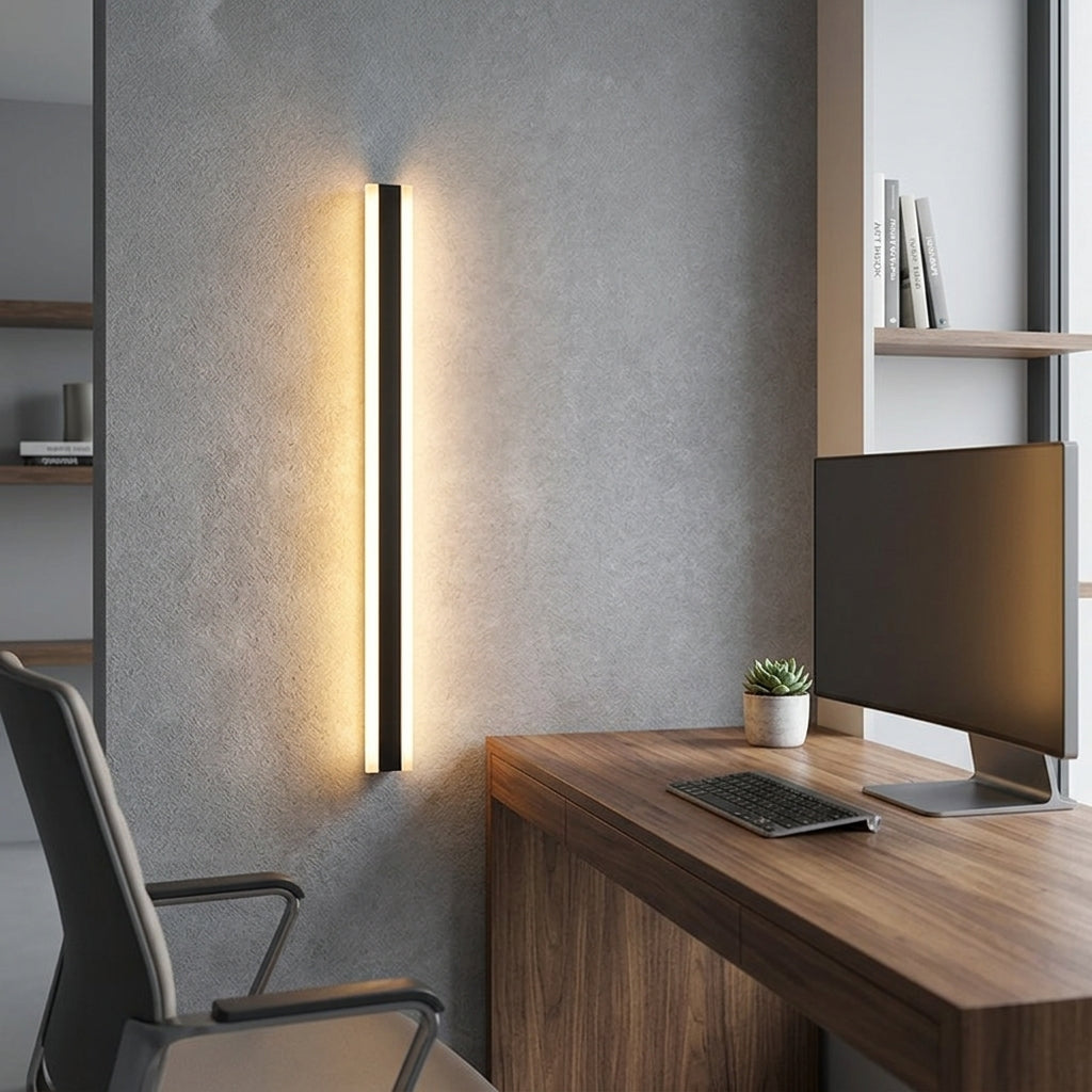 Short black linear LED bar wall light beside a wooden desk in a home office, warm glow