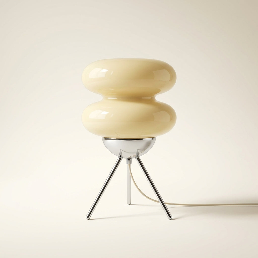 Cream glass macaron table lamp styled with books and decor as a sculptural accent piece.