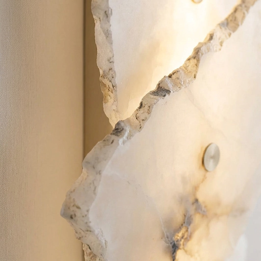 Stacked stone-look wall sconce mounted beside a mirror with a soft ambient glow.