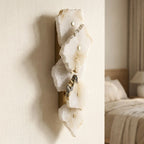 Pair of stone-look wall sconces flanking a bed for symmetrical warm lighting.