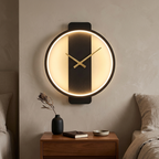 Black round clock wall lamp with gold hands glowing warm above a bedroom nightstand