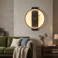 Black round clock wall lamp with gold hands on a living room accent wall