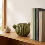 Green cactus-shaped ceramic vase styled empty on an open wooden shelf with books