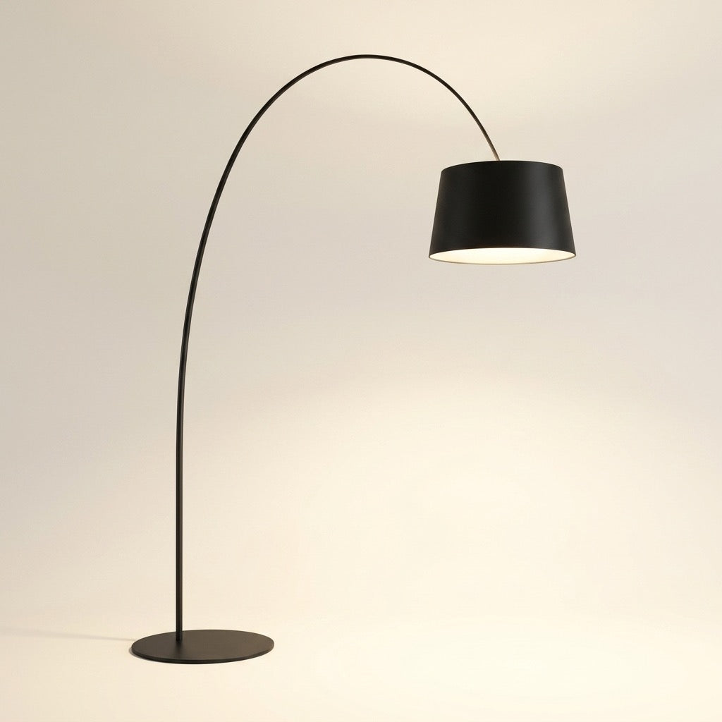 Nordic minimalist arc floor lamp in matte black with a single curved arm, inverted-cone shade and thin round disc base, glowing warm white