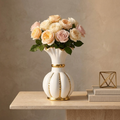 White ceramic vase with gold fluted rim and gold stripes holding garden roses on a console table