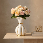 White ceramic vase with gold fluted rim and gold stripes holding garden roses on a console table