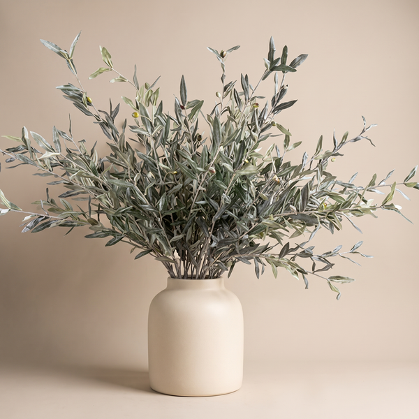 Faux olive branch with muted-green leaves arranged in a ceramic vase on a console table