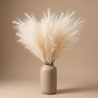 Cream faux pampas grass arranged in a tall ceramic vase on a console table