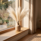 A neutral bundle of artificial pampas grass styled on an open shelf